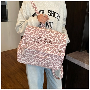 Close-up of pink leopard print canvas backpack with embroidery and metal buckle details