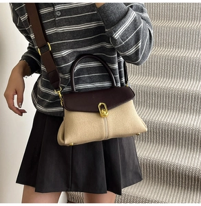 Retro two-tone handbag detail with brown leather trim and golden metal rotary lock buckle