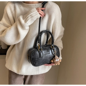 Gros plan du sac oreiller vintage noir avec lettres embossées et breloque peluche