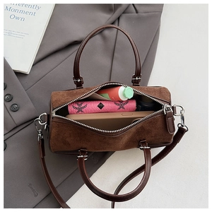 Deep brown matte cylinder bag showing spacious interior with phone and wallet inside