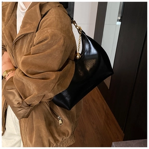 Dettaglio borsa hobo nera con catena dorata e sfera metallica portata a spalla