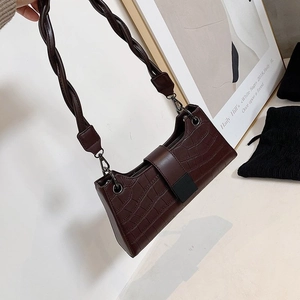 Detail of dark coffee crocodile pattern faux leather handbag with braided shoulder strap