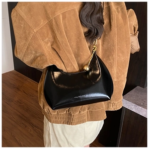 Dettaglio della borsa hobo nera lucida con catena in metallo dorato e ciondolo sferico