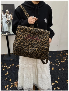 Detail of leopard print canvas backpack showing metal buckle and brand embroidery
