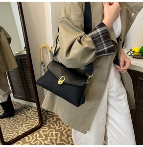 Detail view of a black leather crossbody bag featuring an elegant gold oval twist lock