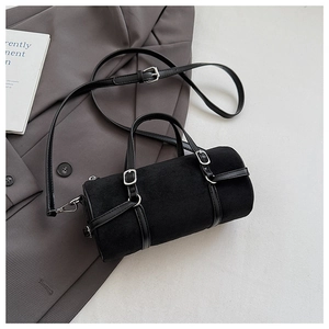 Detail of black cylindrical shoulder bag featuring matte suede texture and silver buckles