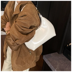Dettaglio della borsa hobo in pelle lucida bianca con finiture dorate indossata da una modella