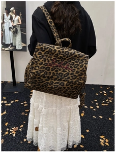 Detail of leopard print canvas backpack with red embroidery on a stylish flap