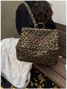 Detail of leopard print backpack featuring pink logo embroidery and metallic gold buckle