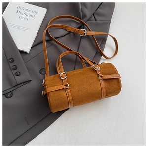 Detailed macro view of brown cylindrical PU bag with smooth leather trim and metal buckles