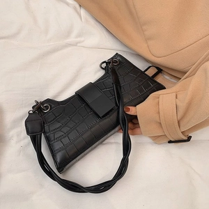 Detail of black crocodile pattern shoulder bag with silver hardware on a wool coat