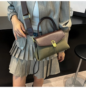 Detail of vintage bicolor handbag showing olive fabric, brown leather, and gold turn-lock