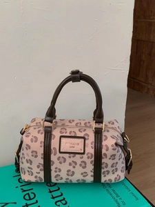 Vintage leopard print Boston bag in pink with brown leather handles on a green book