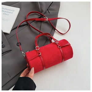 Close-up of a red suede cylinder bag with silver metal hardware and adjustable strap