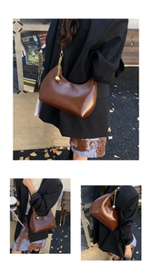 Dettaglio borsa hobo in pelle marrone con tracolla a catena d'oro e ciondolo a sfera
