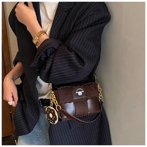 Detail of vintage coffee leather woven shoulder bag with gold chain and donut charm