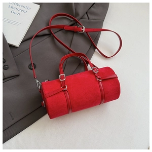 Detail view of red cylindrical bag with suede texture and silver hardware on grey suit