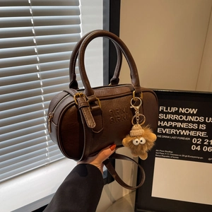 Sac cylindre vintage en cuir marron foncé avec logo en relief et breloque peluche