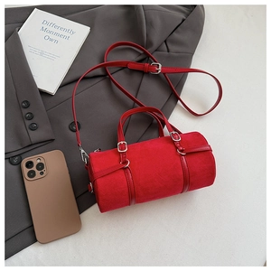 Detail of red cylindrical Boston bag in suede finish with adjustable leather shoulder strap