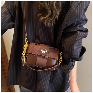 Detail of dark brown leather crossbody bag with woven texture and a gold chain strap
