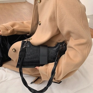Fashionable black crocodile pattern baguette bag with woven strap on camel wool coat