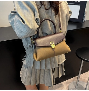Close-up of olive green crossbody bag with leather trim and golden oval twist lock