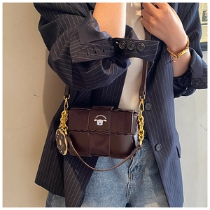 Detail of dark brown quilted mini crossbody bag with wavy edges and doughnut charm