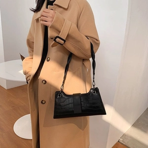 Detail of black crocodile pattern leather underarm bag with unique braided knot shoulder strap