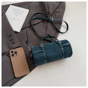 Top view of teal suede cylinder bag with leather handles on a grey blazer