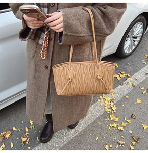 Détail d'un sac cabas marron présentant une texture en cuir plissé matelassé chic