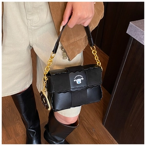 Detail of black leather bag featuring layered wave design and stylish gold chain strap