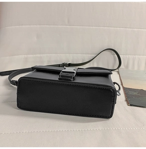 Side view of black PU leather crossbody box bag with silver metal buckle and slim strap