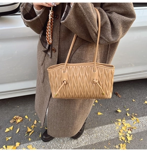 Détail du sac à bandoulière kaki avec matelassage plissé et nœuds en cuir style urbain