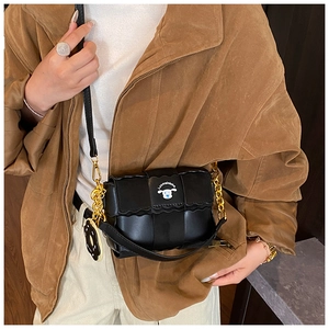 Close-up of black woven biscuit bag with golden chain strap and donut charm detail