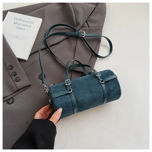 Detailed view of dark teal cylindrical bag with silver hardware and suede texture