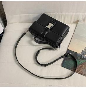 Macro shot of black PU leather crossbody bag featuring a silver metal push-lock buckle
