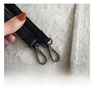 Detail showing high-quality black faux leather strap with dark grey metal swivel hooks