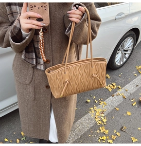 Détail d'un sac cabas plissé en cuir marron clair avec texture matelassée verticale