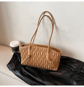 Gros plan du sac fourre-tout caramel avec plis verticaux et détails de nœuds sur la poignée