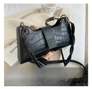 Detail of black crocodile texture bag with square buckle and woven shoulder strap