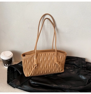 Détail du sac cabas plissé kaki avec bandoulière nouée sur fond en cuir noir