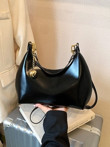 Borsa hobo nera lucida con catena dorata su valigia argentata, stile chic ed elegante