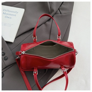 Detailed view of the red cylinder bag's zipper opening with cream fabric lining and pocket