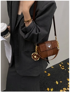 Retro brown crossbody bag with woven texture and donut charm styled on a model