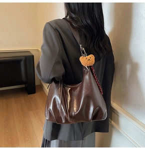 Detail of dark brown PU leather hobo bag with teddy bear charm and pattern silk scarf