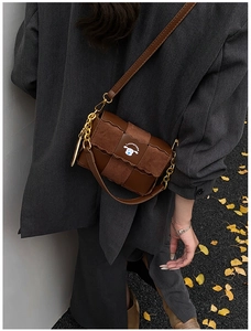 Detail of brown woven faux leather crossbody bag featuring gold chain and retro autumn design