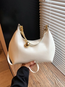 Elegante borsa hobo beige con catena dorata e ciondolo a sfera su legno