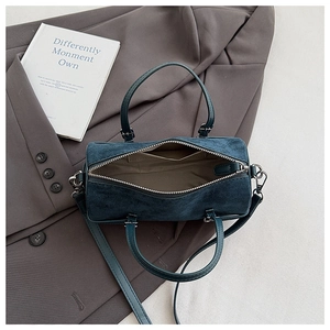 Detailed interior of teal suede cylinder bag showing lining, side pocket and zipper