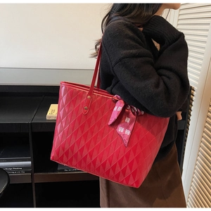 Detalle de bolso tote rojo acolchado con pañuelo de seda llevado por una modelo