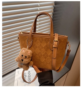 Detail of caramel suede bucket bag showing embossed logo pattern and plush puppy charm